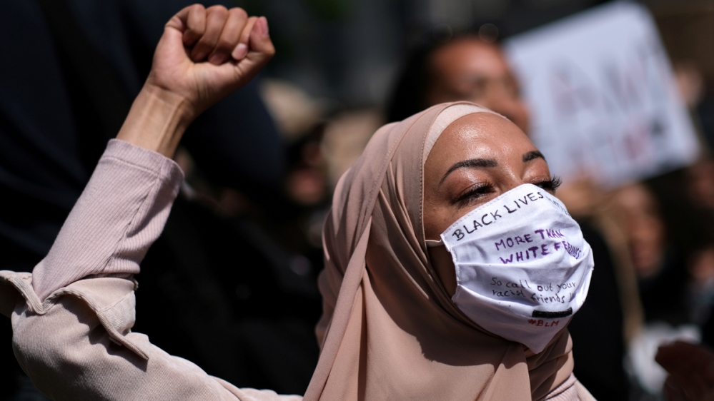 A woman wearing a face mask raises her fist during a protest against the death in Minneapolis police custody of African-American man George Floyd, at Hermannplatz square in Neukoelln district, Berlin,