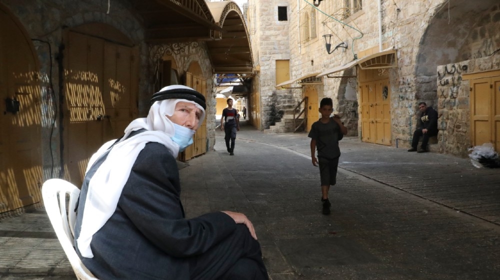 Palestinians walk in a street in the town of Hebron in the occupied West Bank on June 21, 2020, after Palestinian Authority said it was temporarily closing the cities of Hebron