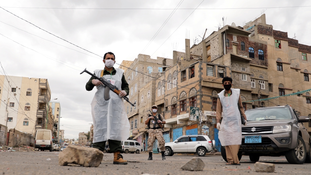Security men wearing protective masks stand on a street during a 24-hour curfew amid concerns about the spread of the coronavirus disease (COVID-19), in Sanaa, Yemen