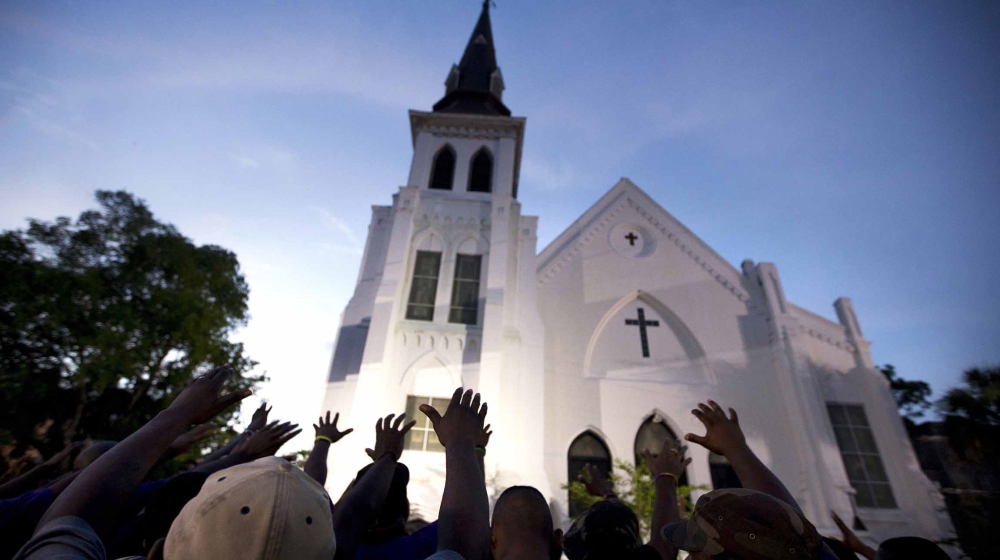 In this June 19, 2015 file photo, the men of Omega Psi Phi Fraternity Inc. lead a crowd of people in prayer outside the Emanuel AME Church, after a memorial for the nine people killed by Dylann Roof i