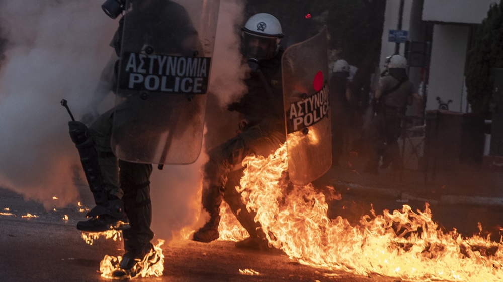 Riot police officers try to avoid patrol bombs thrown by protesters outside the Greek Parliament during a demonstration against new protest law in Athens, on Thursday, July 9, 2020. Violence has broke