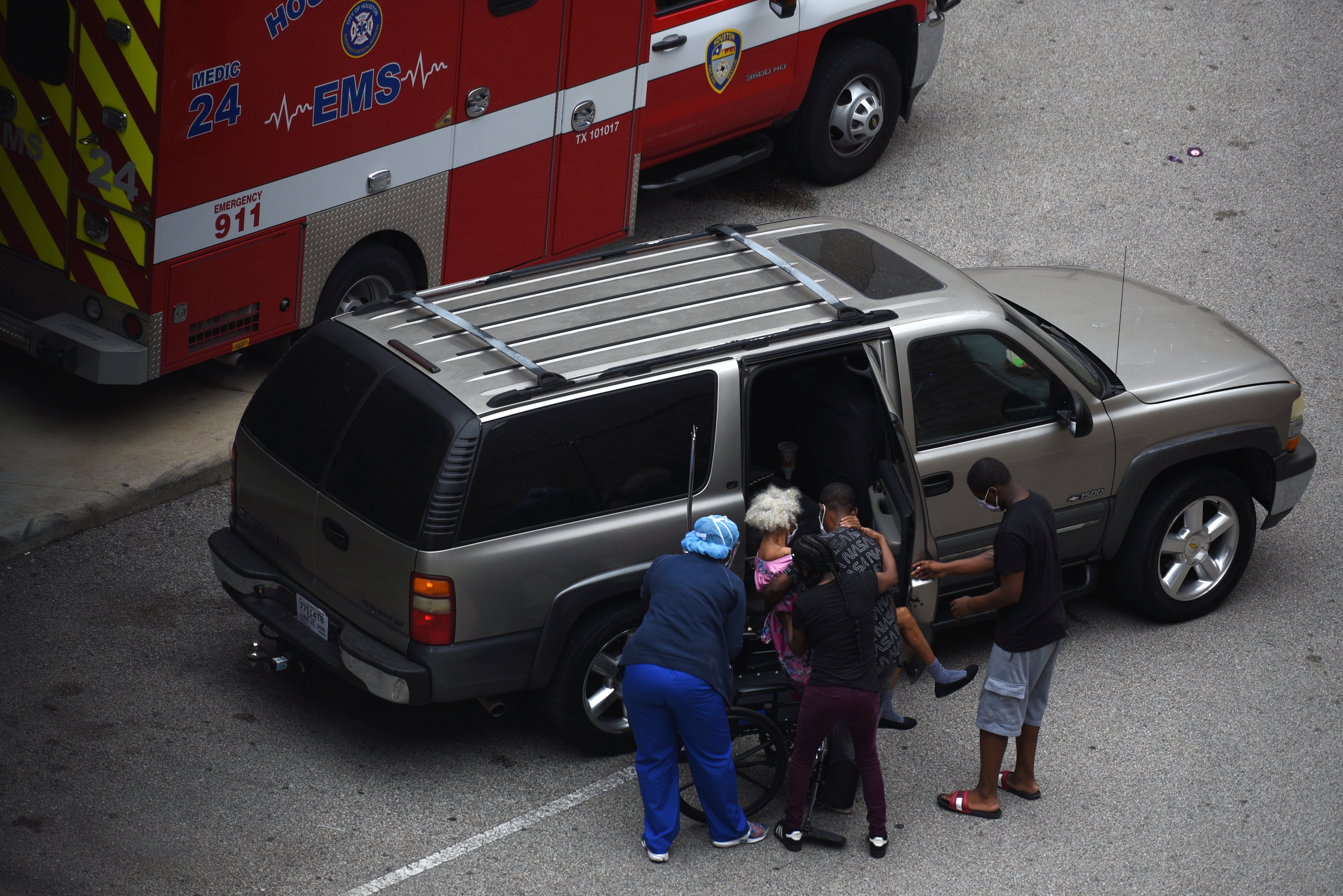 A nurse helps people put a woman in a wheelchair at a hospital in Houston, Texas, one of the states which has seen the sharpest spikes in reported coronavirus cases