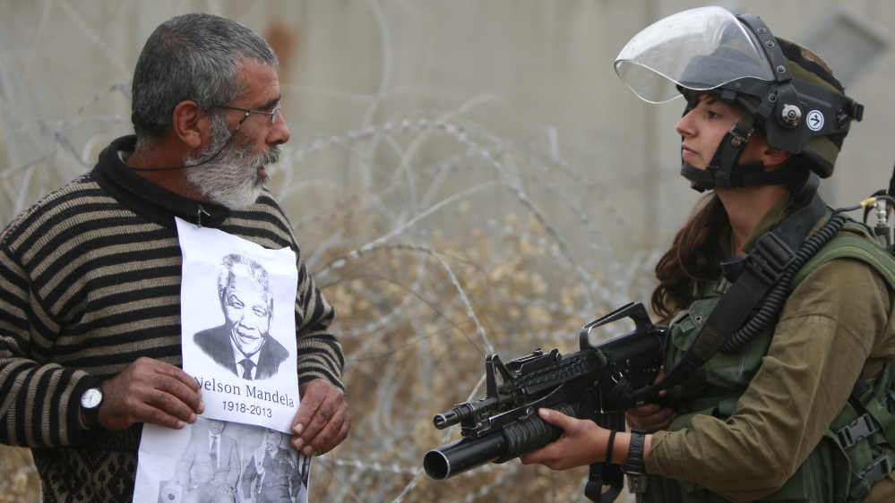 A Palestinian demonstrator holds portraits of late South African Leader Nelson Mandela a