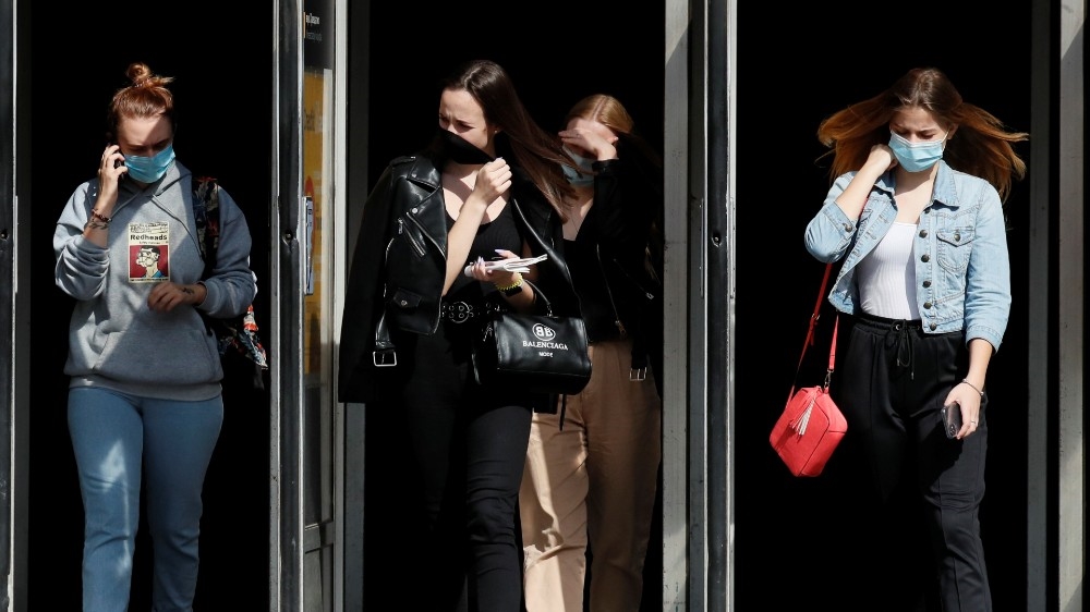 People wearing protective face masks walk out of a metro station in Kyiv