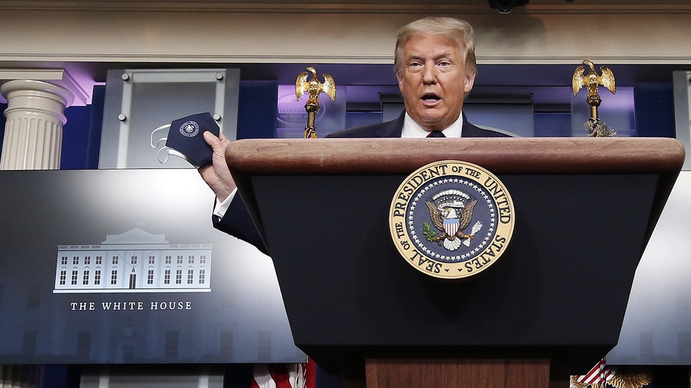 US President Donald Trump holds up his face mask at the White House press briefing on July 21