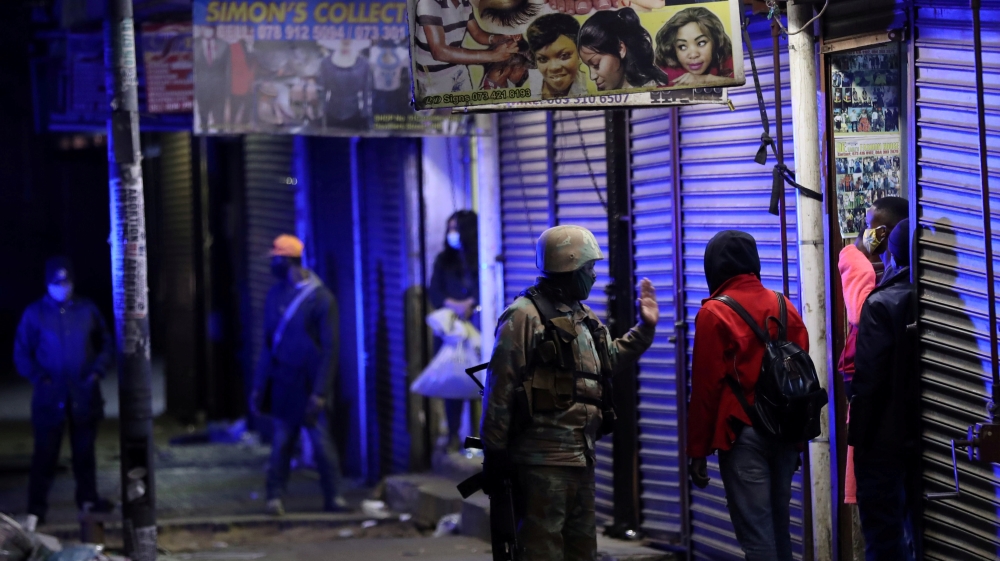 A member of the South African military talks to a man during a patrol as a nighttime curfew is reimposed in Johannesburg, South Africa