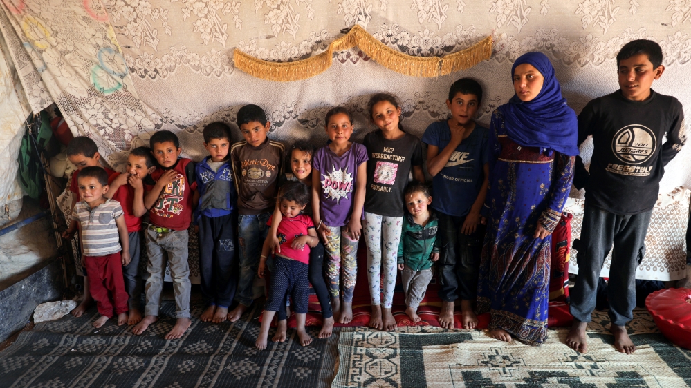 The children of Ahmad Yassin al-Ali and his wife Fawza Umri pose for a picture inside their tent, at Atmeh camp, near the Turkish border