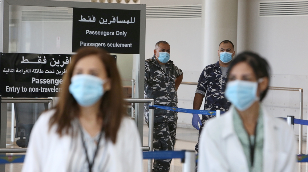 Health workers and members of internal security forces wearing face masks stand inside Beirut international airport