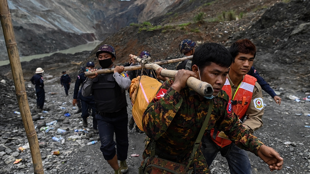 Myanmar soldiers and Red Cross workers carry a body recovered from the site of a landslide