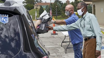 A motorist is handed a bag containing information about open positions at a drive-thru job fair in Omaha, Nebraska