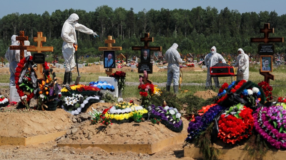 Gravediggers wearing personal protective equipment (PPE) bury a person, who presumably died of the coronavirus disease, in the special purpose section of a graveyard on the outskirts of Saint Petersburg, Russia
