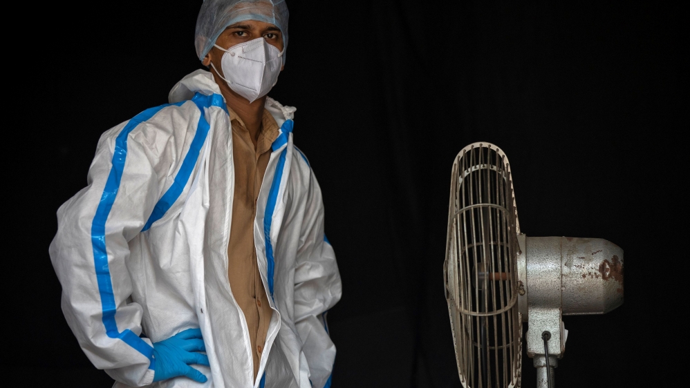 A health worker in personal protective equipment takes a break while waiting for people to collect samples to conduct COVID-19 tests