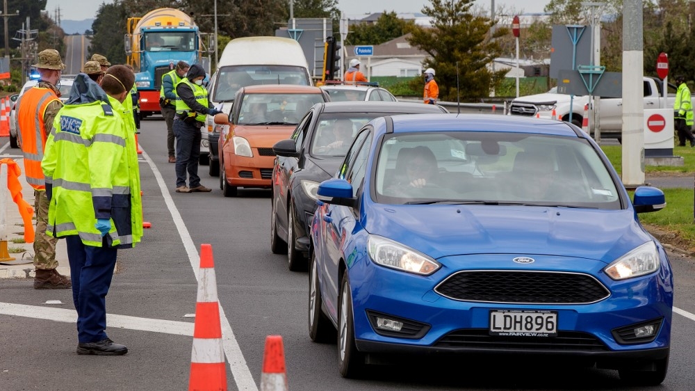 Police and military personnel check vehicles leaving Auckland at a COVID-19 checkpoint outside the city
