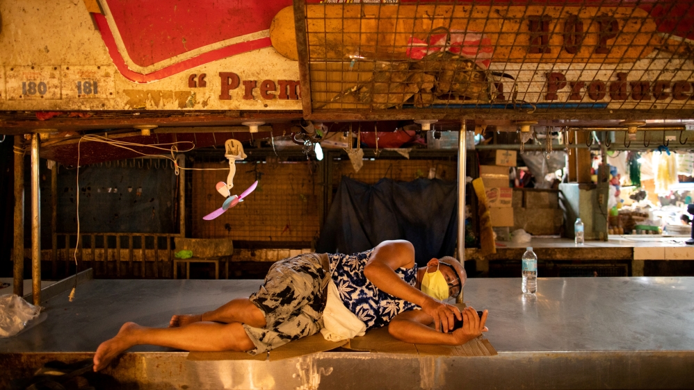 A meat vendor rests at a public market where wearing face masks and face shields is mandatory, in Taytay, Rizal province, Philippines