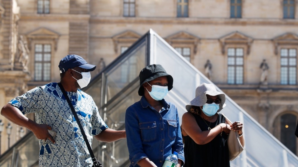 People wearing protective masks walk near the Louvre Museum as France reinforces mask-wearing as part of efforts to curb a resurgence of the coronavirus disease (COVID-19) across the country, in Paris, France