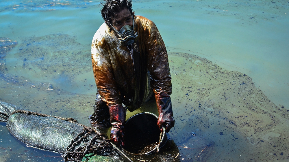A man scoops leaked oil from the vessel MV Wakashio, belonging to a Japanese company but Panamanian-flagged, that ran aground near Blue Bay Marine Park off the coast of south-east Mauritius on August