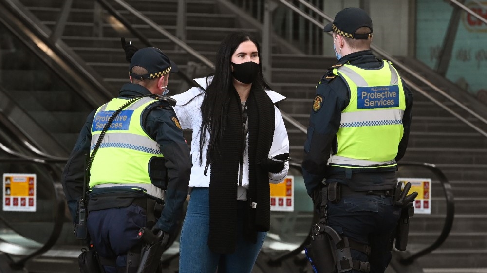 Protective services officers speak to a woman at the Southern Cross Station in Melbourne on August 7, 2020, as the city goes into a strict new lockdown