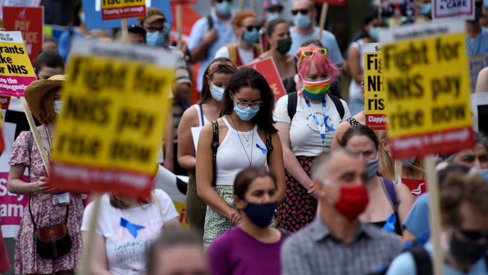 Demonstrators hold placards that read ‘Fight for NHS, pay rise now’