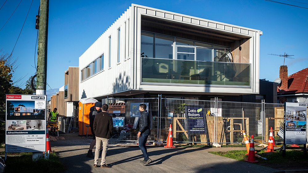 People stand outside new residential property in Auckland on June 19, 2020. - New Zealand''s economy suffered its biggest contraction in 29 years during the first three months of the year, official dat
