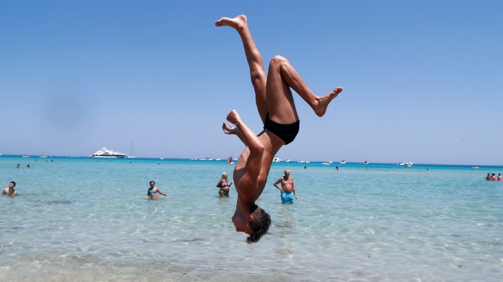 A man performs a backflip at Mondello beach, following the outbreak of the coronavirus disease (COVID-19) in Palermo, Italy, July 31, 2020. REUTERS/Guglielmo Mangiapane T