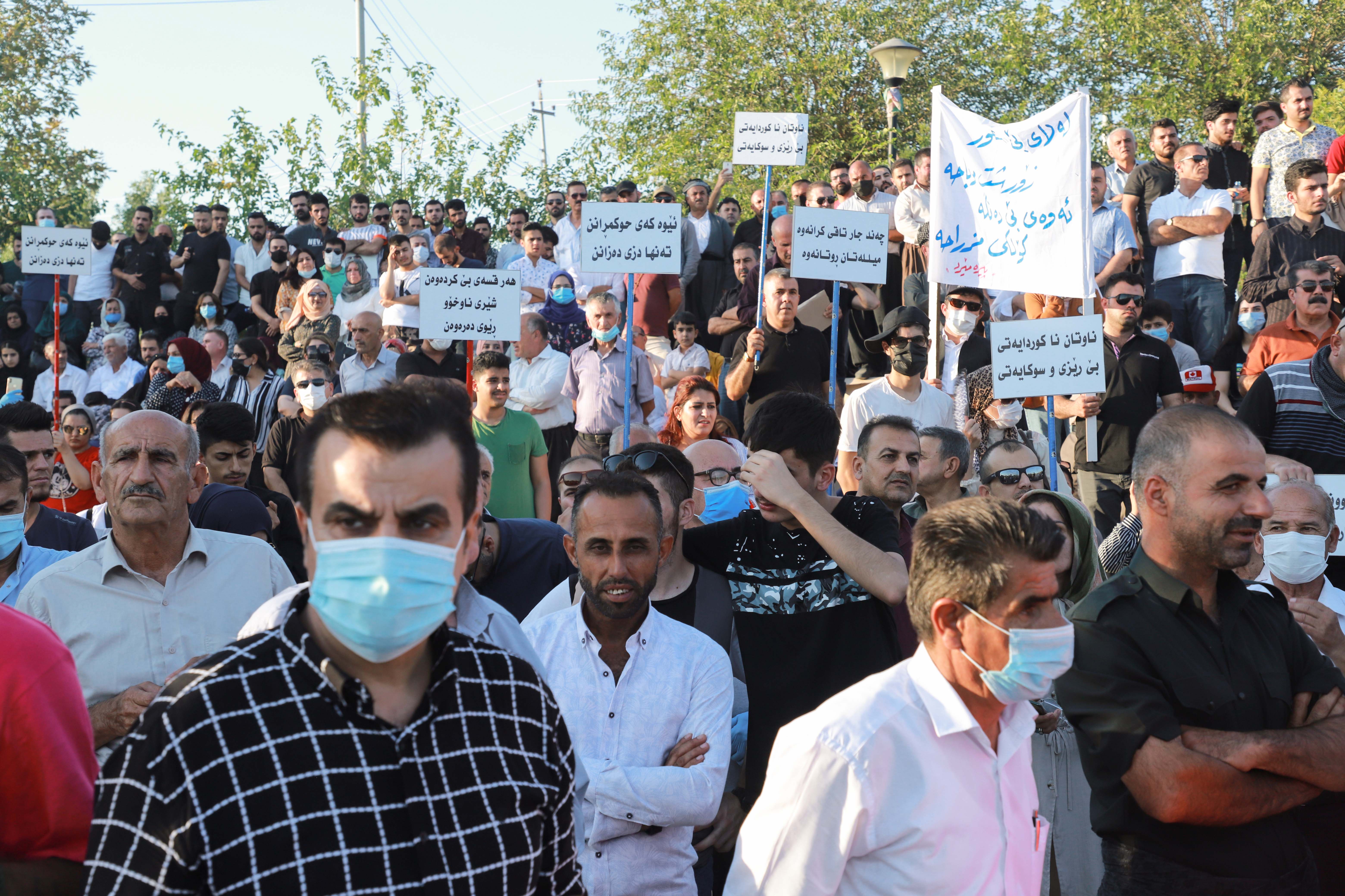 Iraqi Kurds lift placards during a demonstration at the the Freedom Park in the center of Sulaimaniyah in Iraq's autonomous Kurdish region, on August 12, 2020 [File: Shwan Mohammed/AFP]