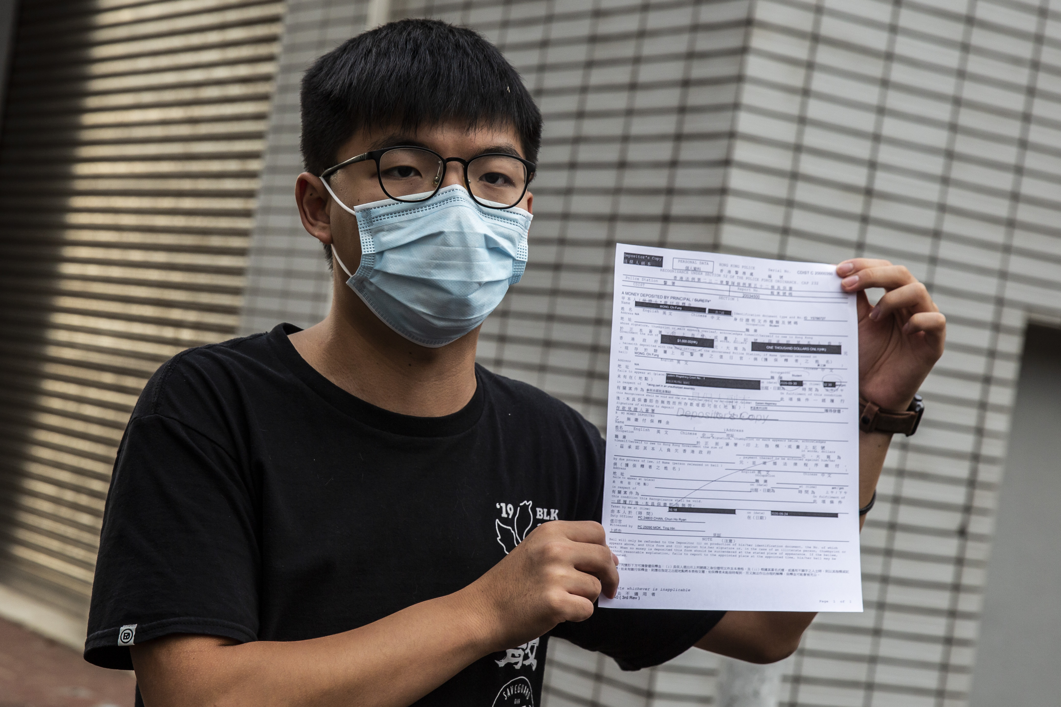 Pro-democracy activist Joshua Wong speaks to the media while holding up a bail document after leaving Central police station in Hong Kong on September 24, 2020,