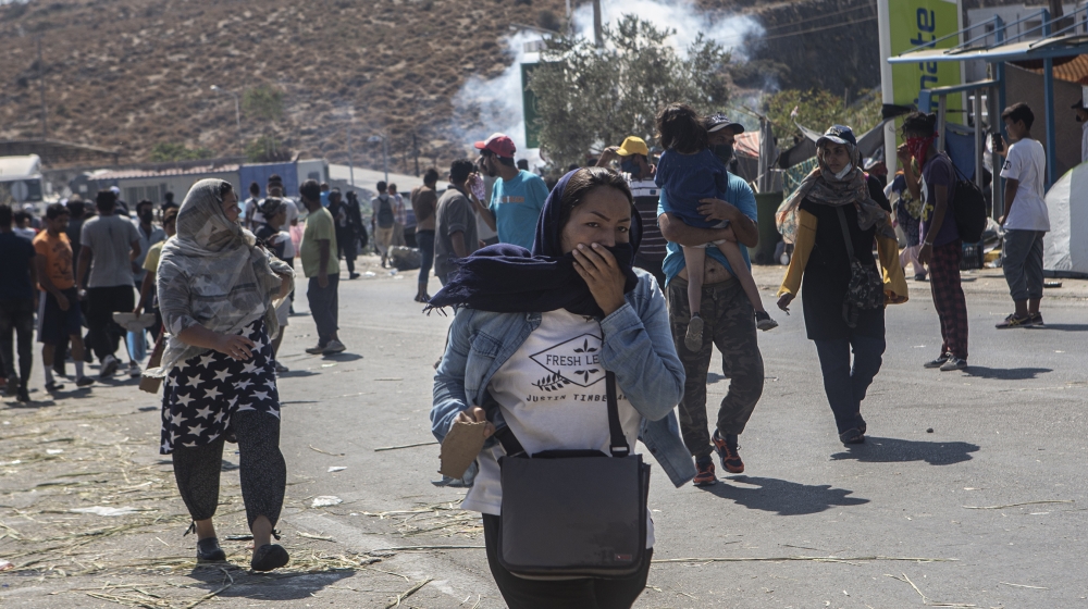 An Afghan woman runs to escape tear gas that Greek riot police fired against the crowd after a peaceful demonstration in Kara Tepe, Lesbos