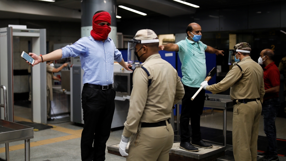 Security guards frisk commuters at a metro train station New Delhi