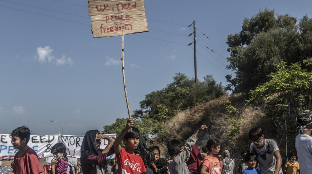 An Afghan boy holds a sign saying ‘We need peace, freedom’ during a peaceful demonstration on September 12, demanding to be allowed to leave Lesbos island.