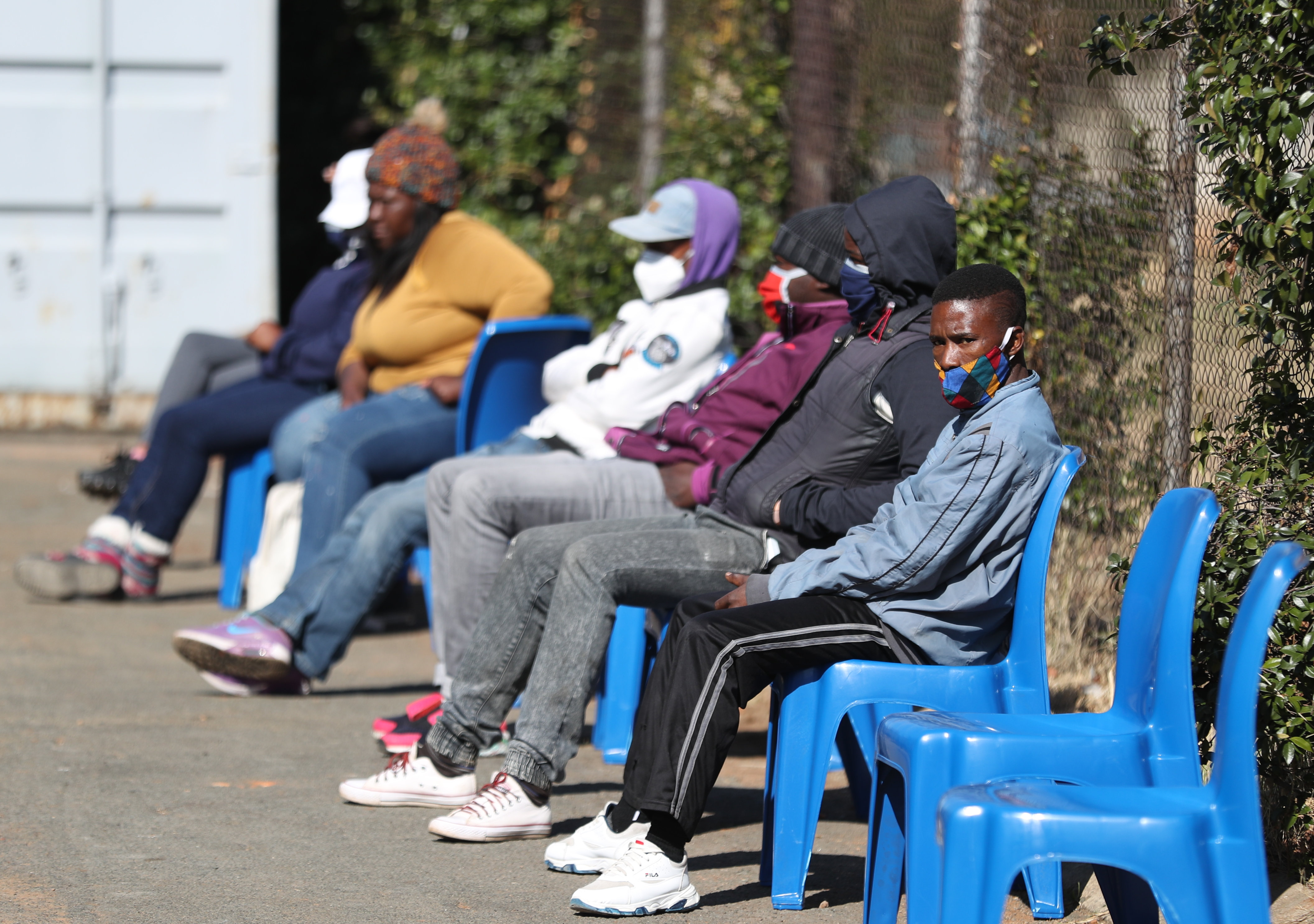 Some of the first South African COVID-19 vaccine trialists wait outside a clinic in Soweto [Siphiwe Sibeko/AFP]