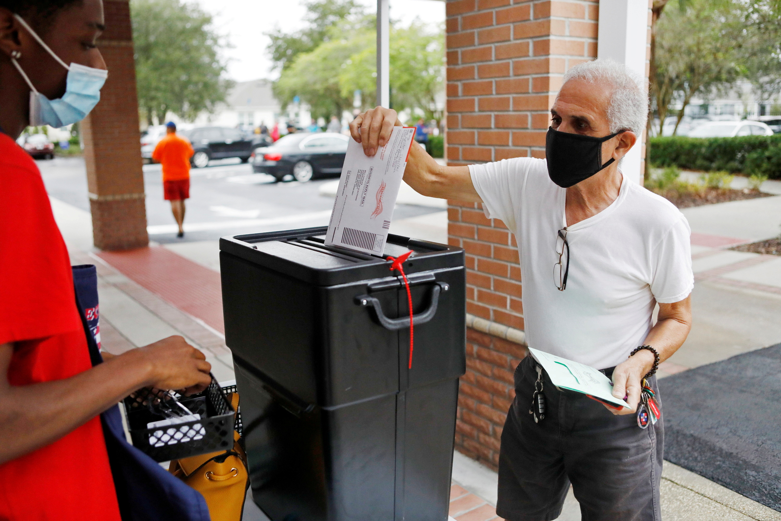 Florida resident Valentine Lugo casts his mail-in ballot at the Winter Garden Library polling station as early voting begins ahead of the election in Orlando, Florida, the United States