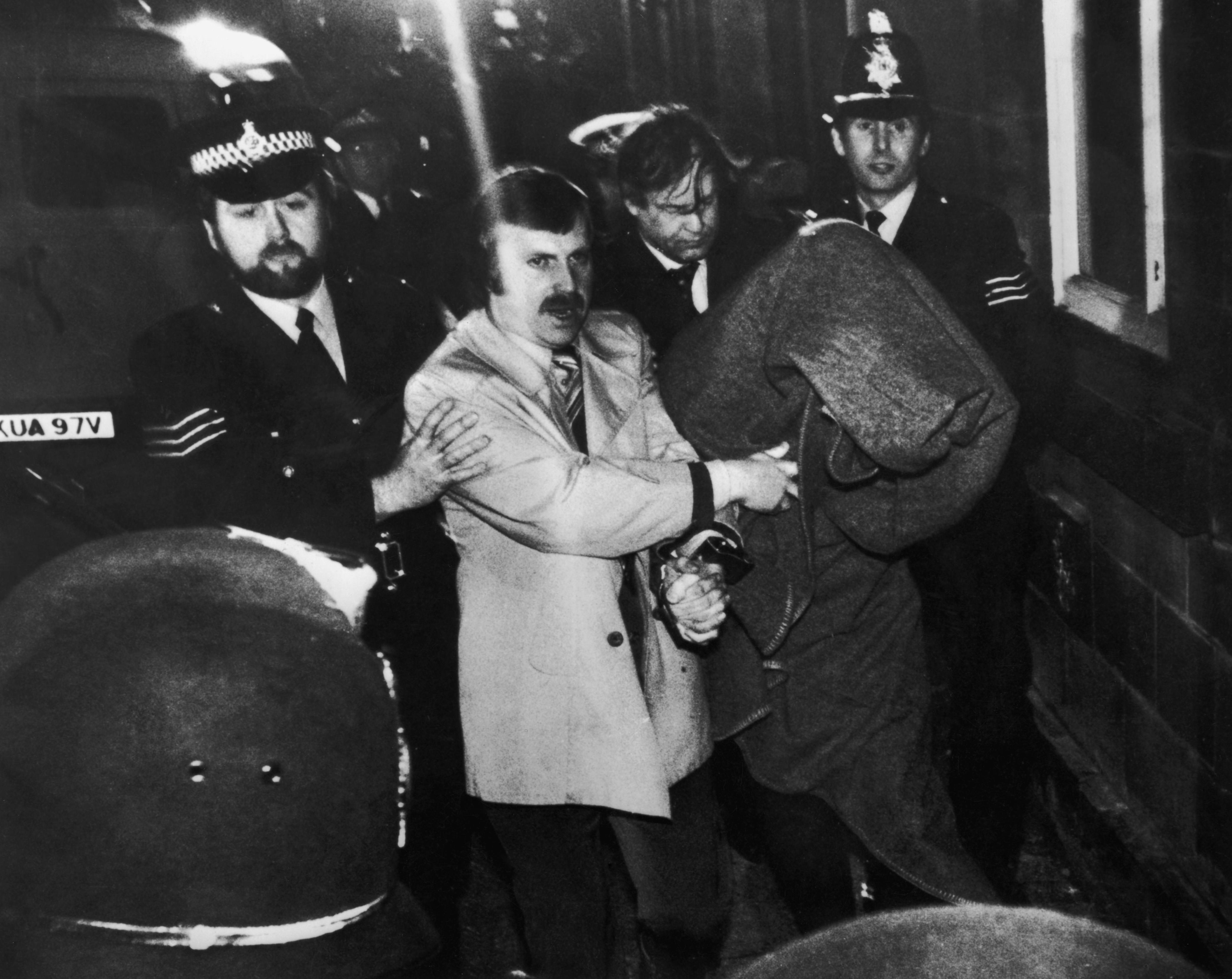His head covered with a blanket, Peter Sutcliffe is escorted into Dewsbury Magistrates Court to be charged with murder on January 6, 1981