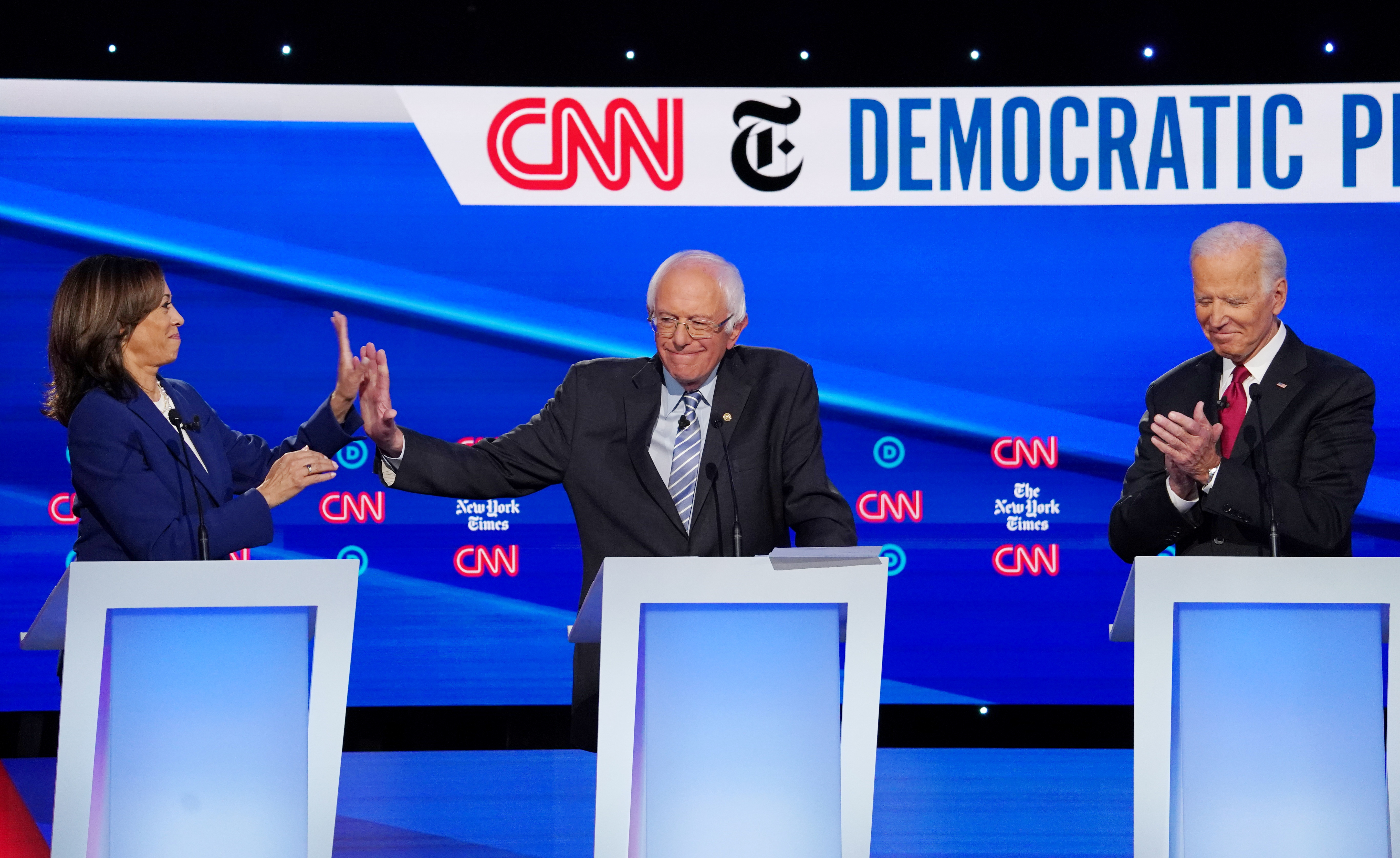 Kamala Harris high fives Bernie Sanders as Joe Biden applauds him for his response to a question during the fourth US Democratic presidential candidates election debate at Otterbein University in Westerville, Ohio US, October 15, 2019 [Shannon Stapleton/Reuters]