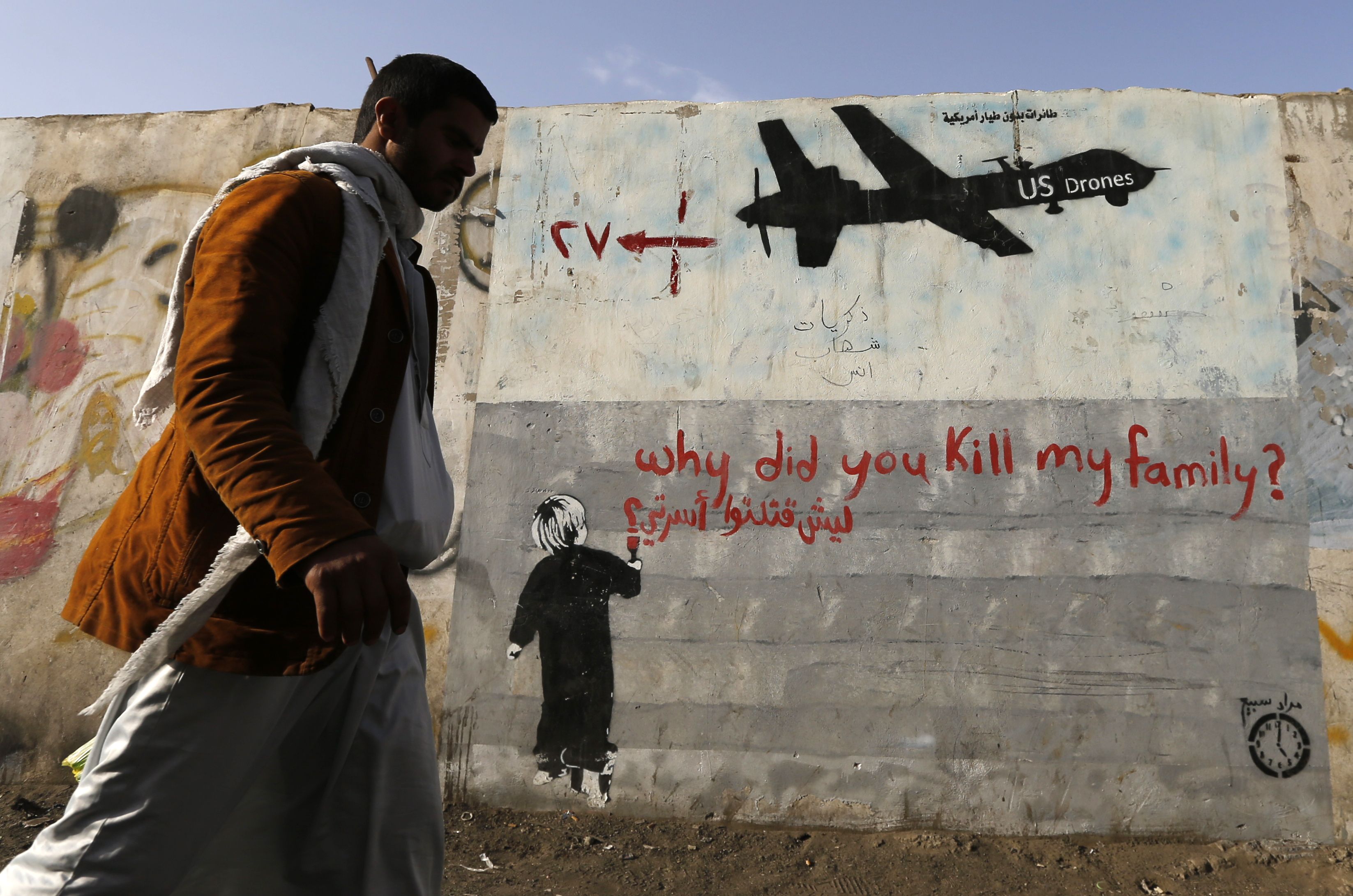 A man walks past a graffiti denouncing attacks by US drones in Sanaa, Yemen