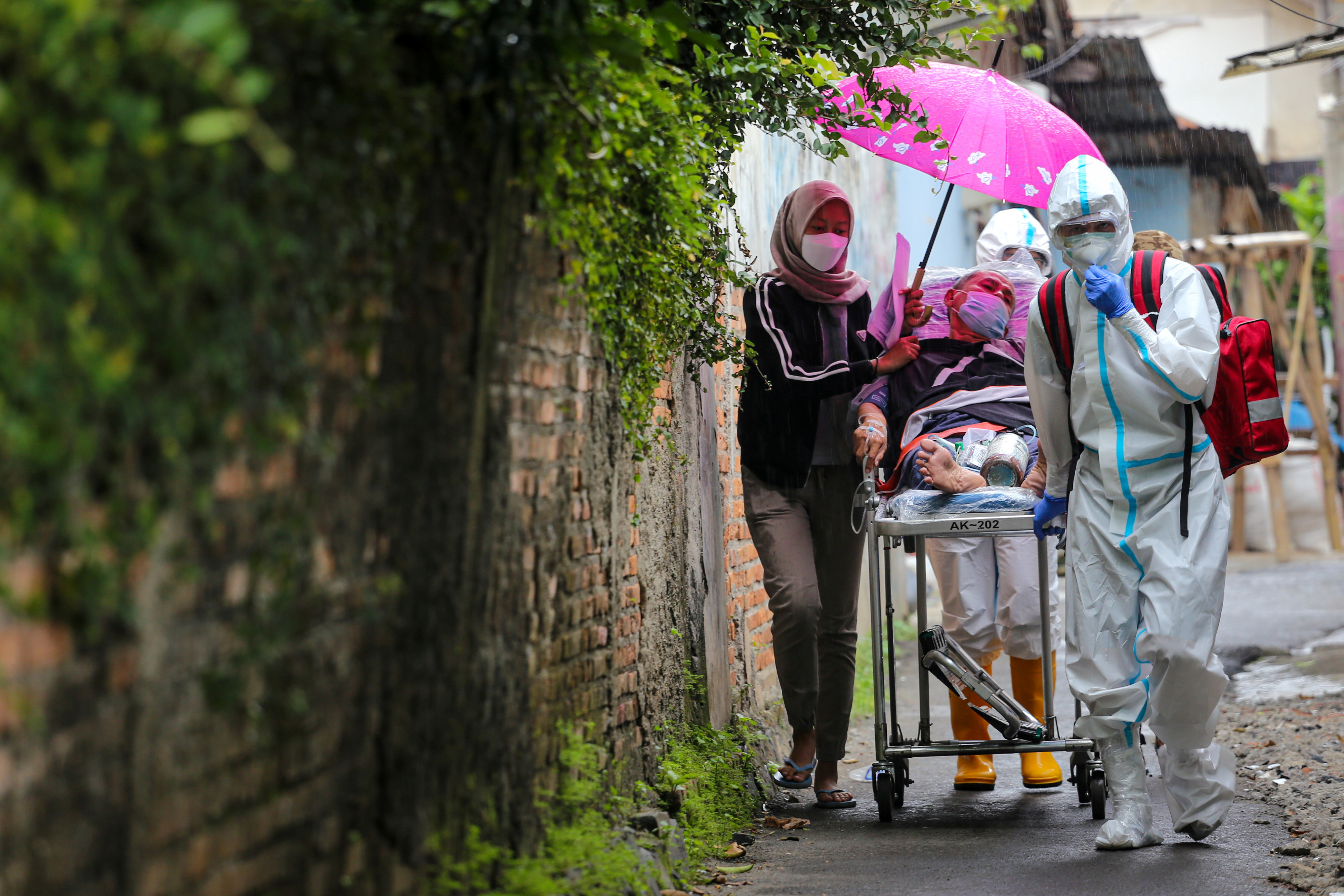 Healthcare workers wearing protective suits carry a COVID-19 patient amid the coronavirus pandemic in Jakarta, Indonesia