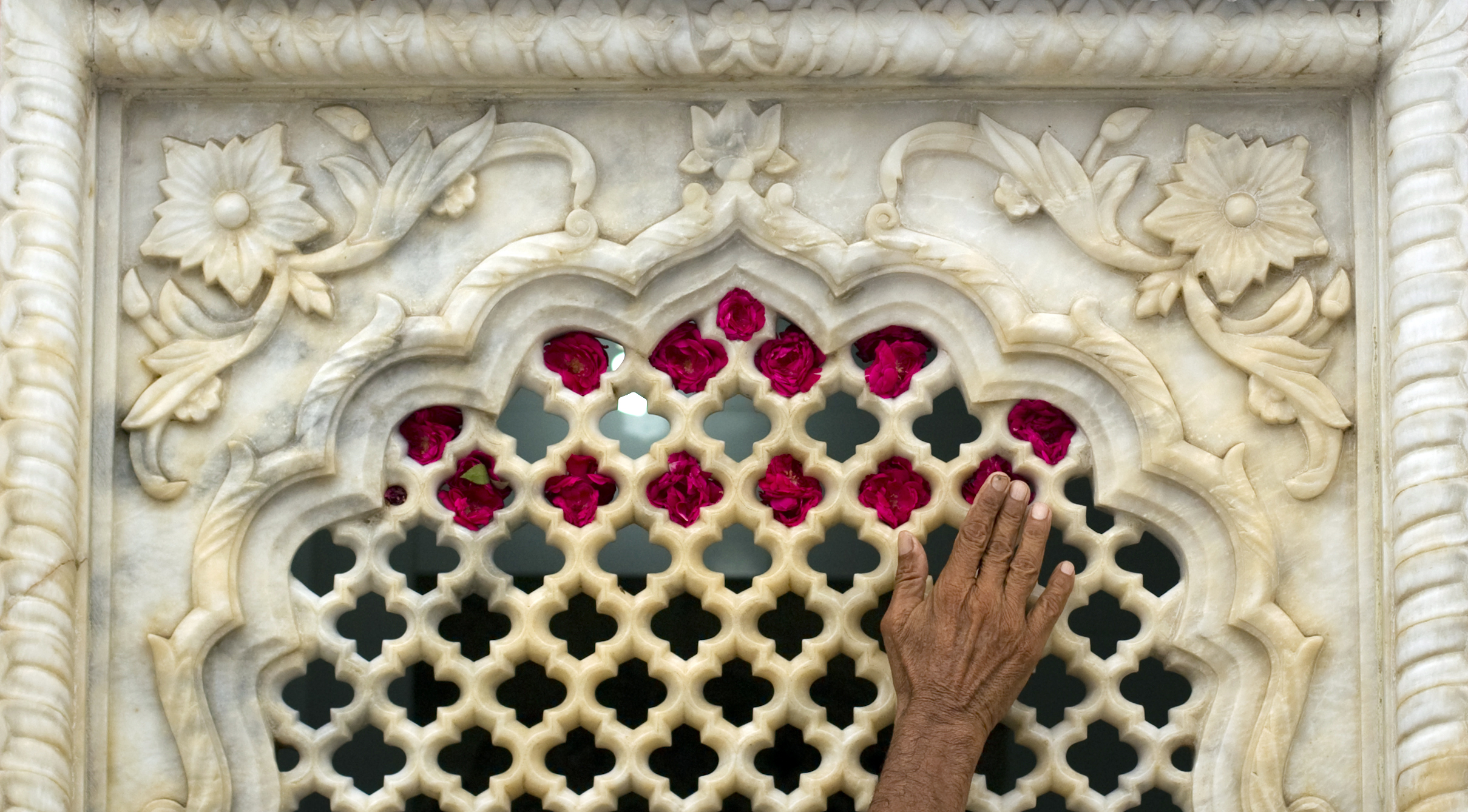 A man adorns the marble walls of the Data Darbar Sufi shrine with roses after a suicide bombing there in July 2010