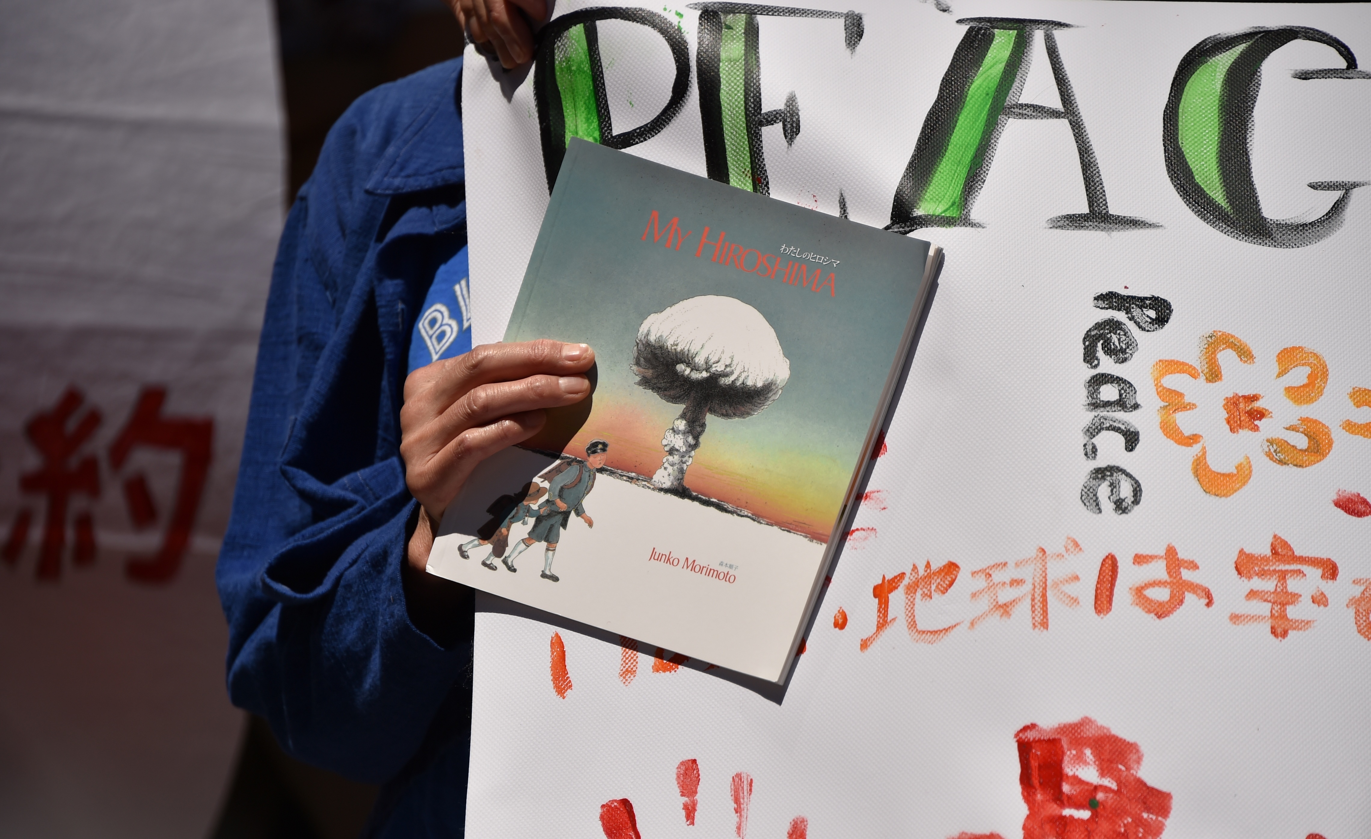 A protestor holds a sign and a banner to rally against nuclear weapons in Australia in February 2018.