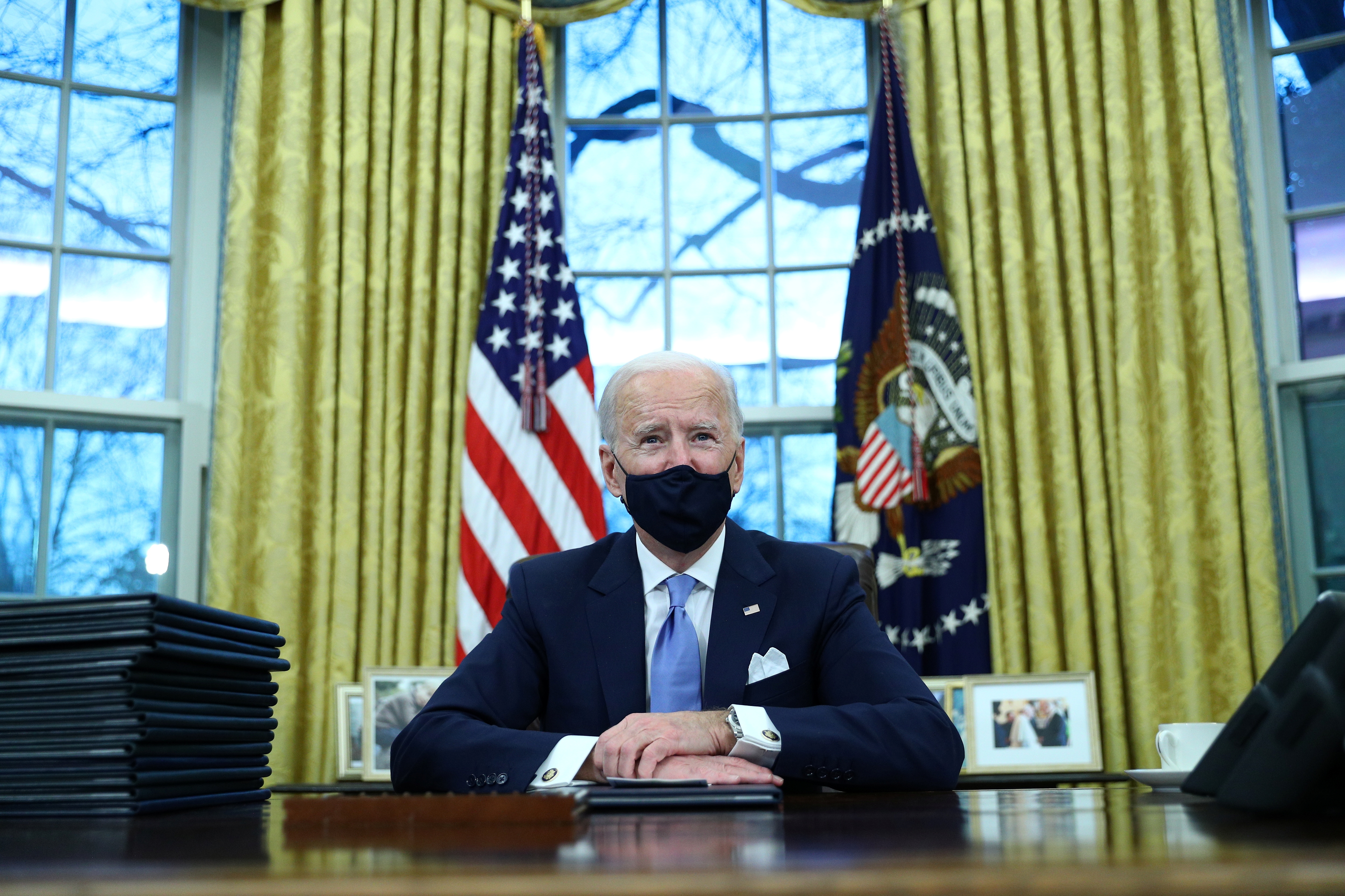 Joe Biden signs executive orders in the Oval Office of the White House in Washington, DC, after his inauguration as the 46th president of the United States, January 20, 2021 [Tom Brenner/Reuters]