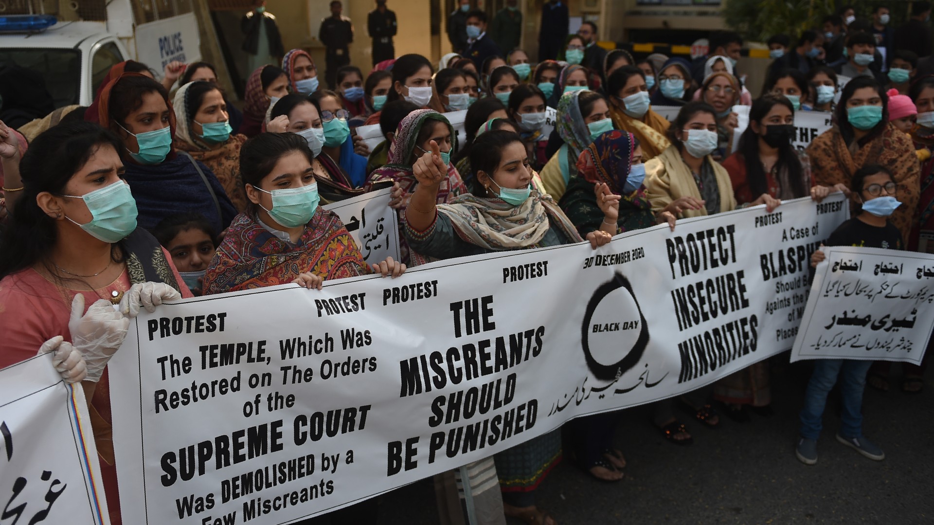 Members of Pakistan Hindu Council stand behind a banner during a protest against a mob attack on the temple