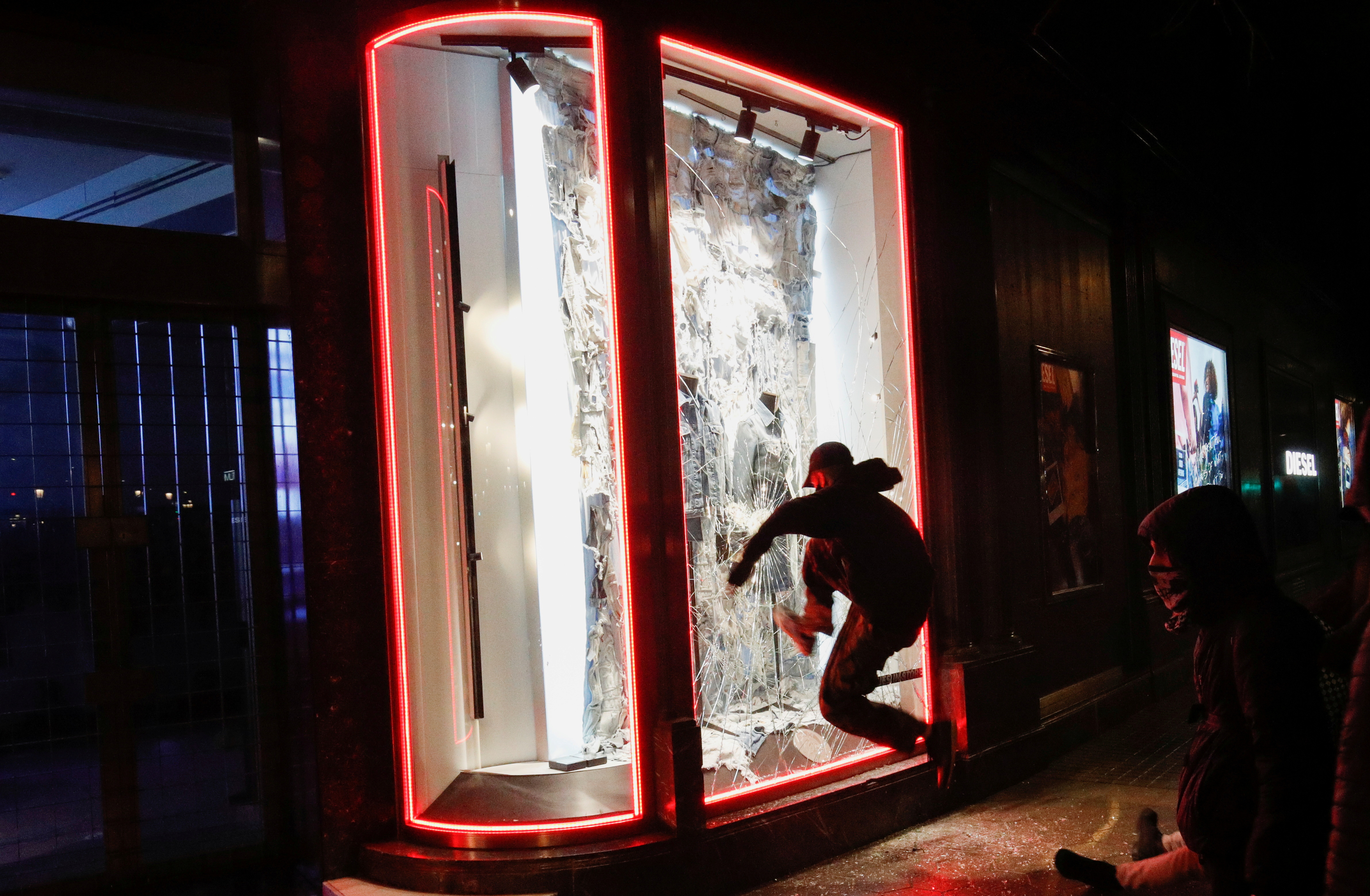 A demonstrator kicks a window of a shop as supporters of arrested Catalan rapper Pablo Hasel protest in Barcelona, Spain, February 20, 2021