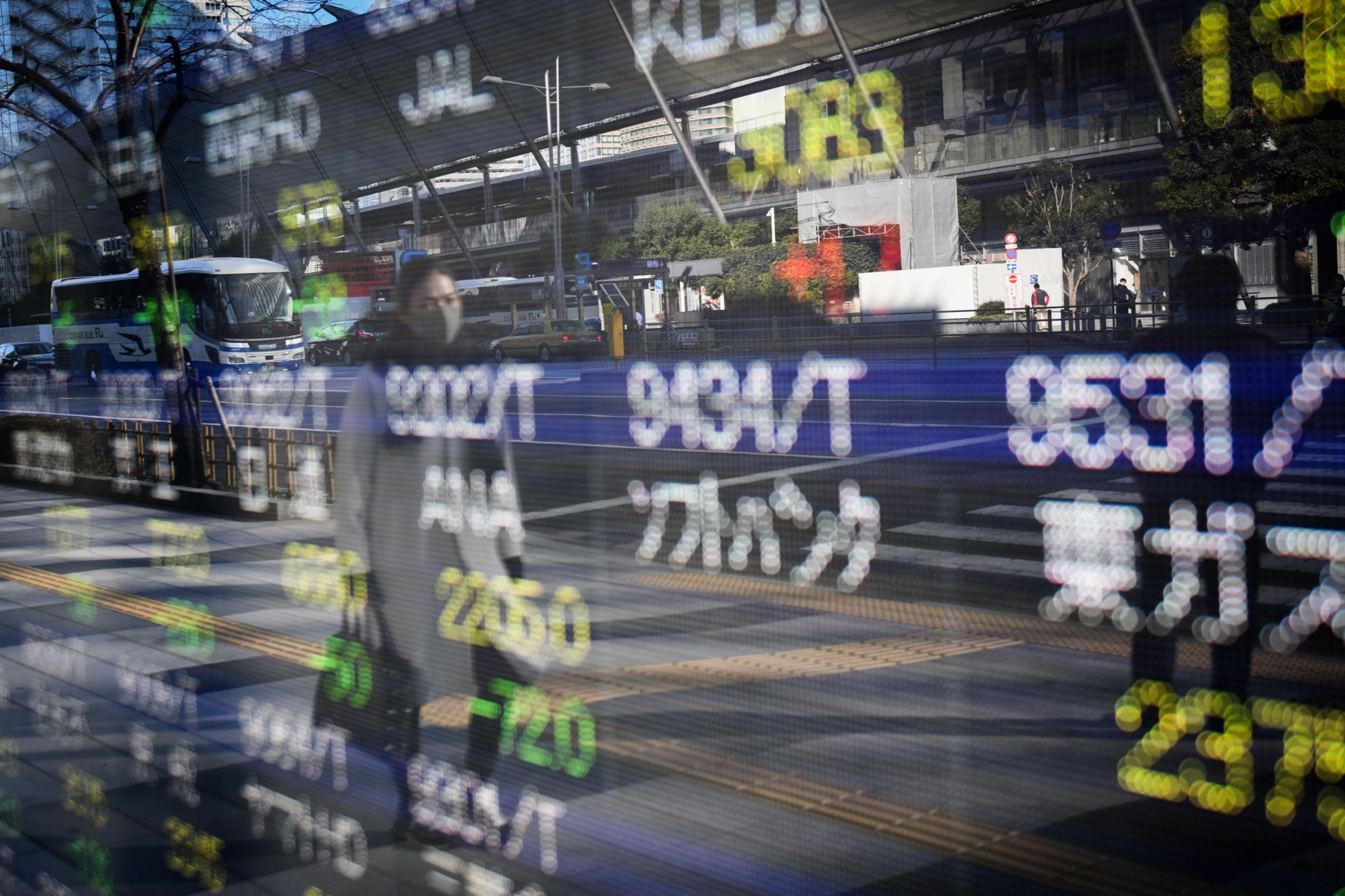 man walking past stock board in Japan