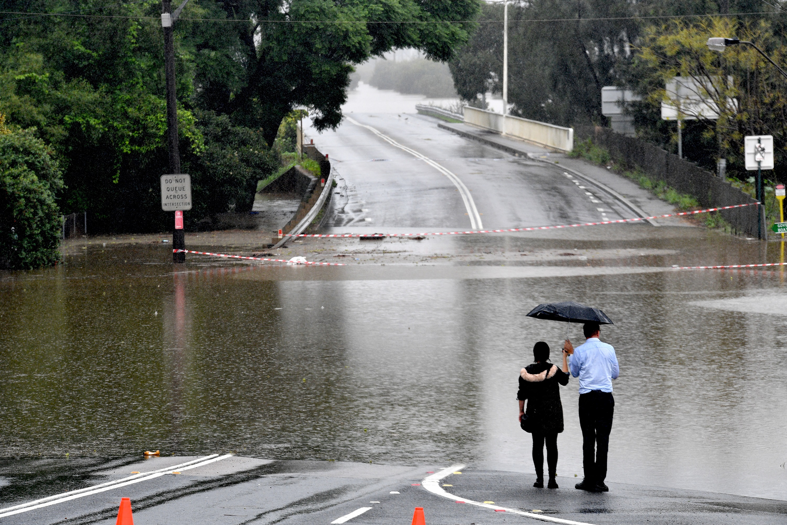 People look out at a flooded residential area in the Windsor area in northwestern Sydney on March 23, 2021, after torrential rain in Australia’s southeast