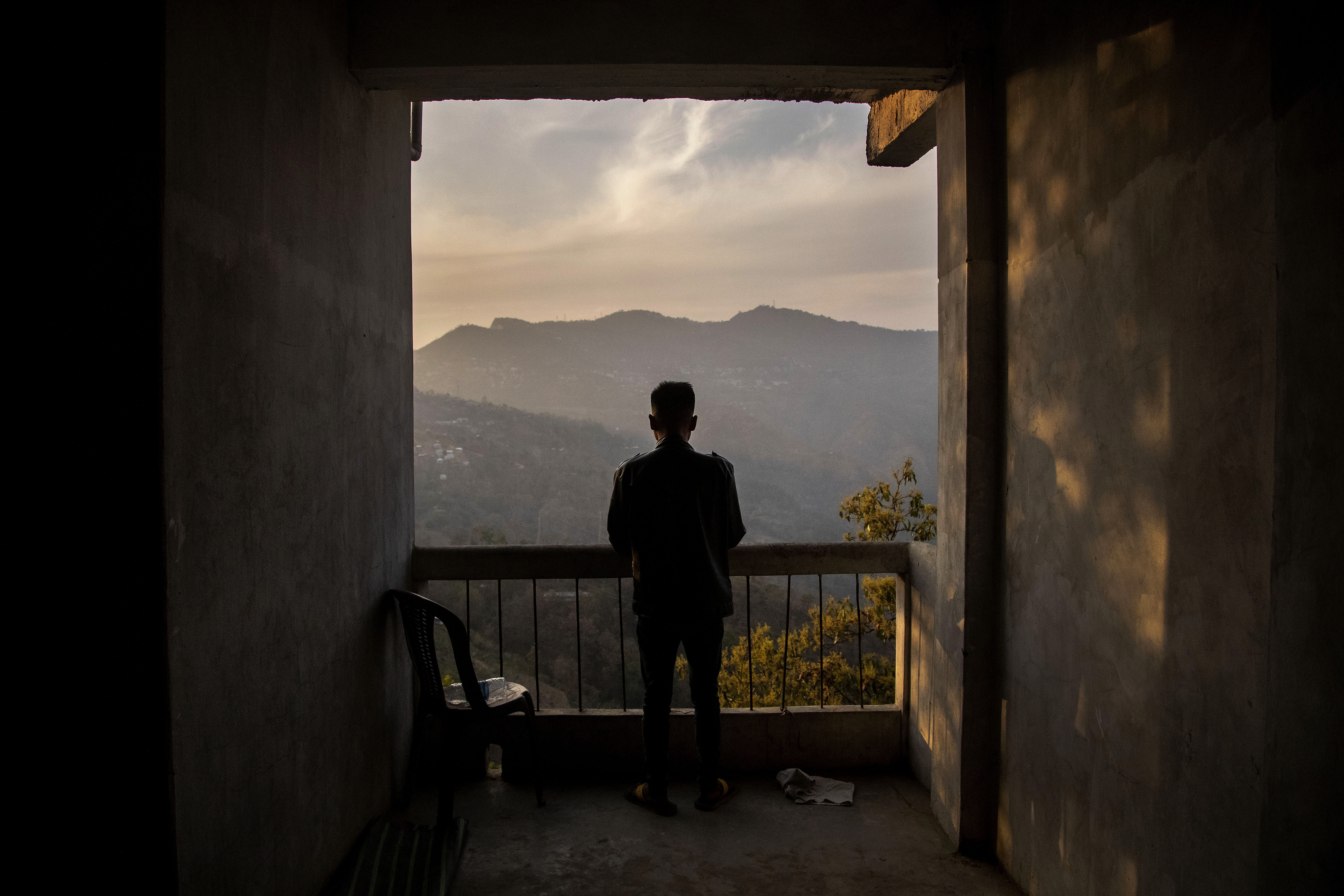 A police officer who fled from Myanmar following a military coup looks out to the mountains from an undisclosed location bordering Myanmar, in the northeastern Indian state of Mizoram [File: Anupam Nath/AP]