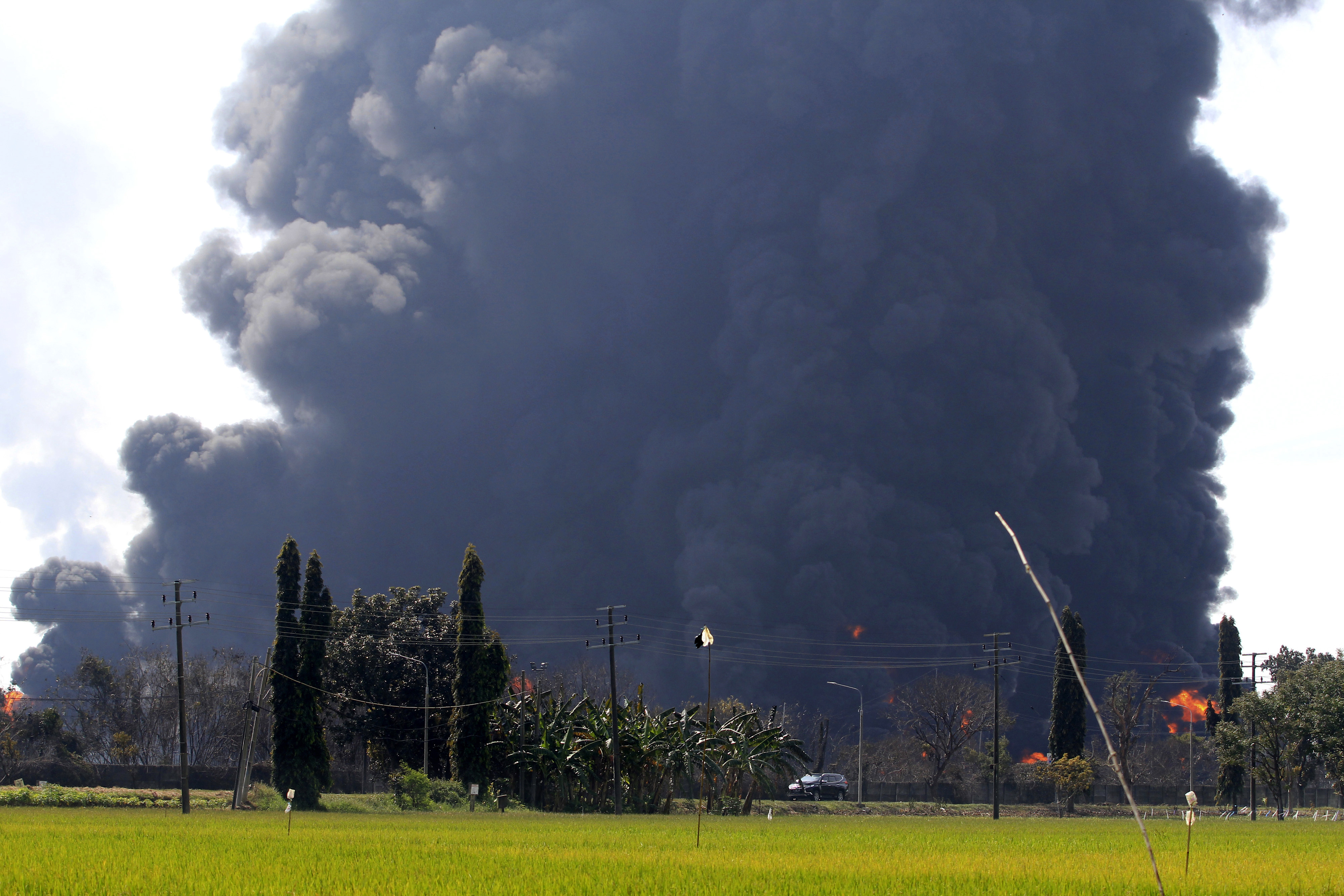 A car passes by as smoke billows from a fire at the state-owned Pertamina Balongan Refinery in Indramayu, Indonesia on Monday