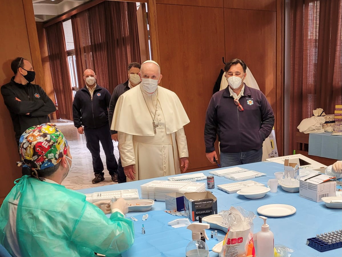 Pope Francis speaks to medical staff on Good Friday at a vaccination centre in the Paul VI Hall where the poor and homeless are being inoculated, at the Vatican [Vatican Media via Reuters]
