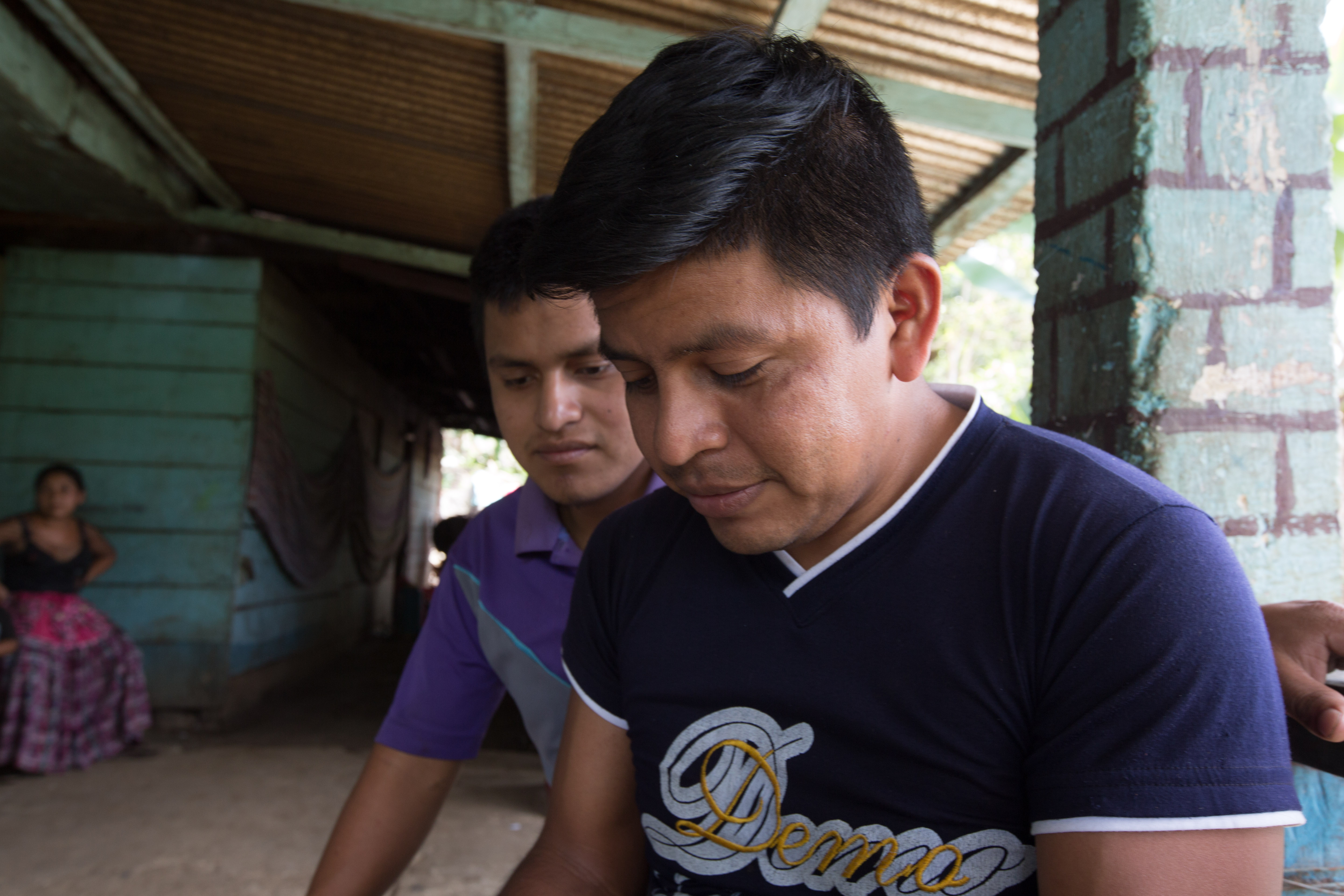 Walter Choc sits with his cousin in Campur in April, looking at photos from their attempt to migrate to the United States