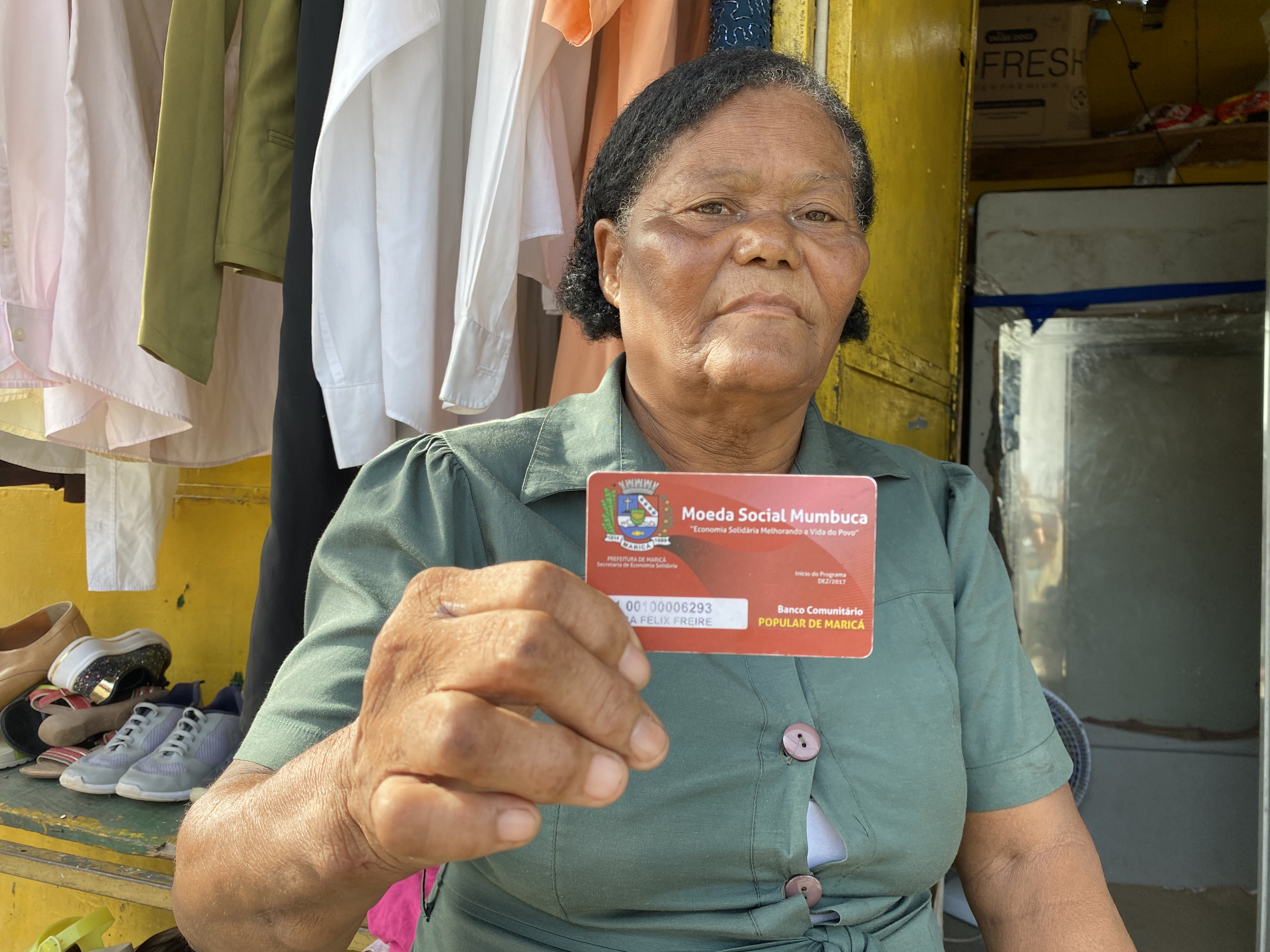 Jandira Freitas shows off her mumbuca card — aid in the form of digital currency — that helped her start her own small business in the socialist city of Marica, Brazil, where she lives [Monica Yanakiew/Al Jazeera]