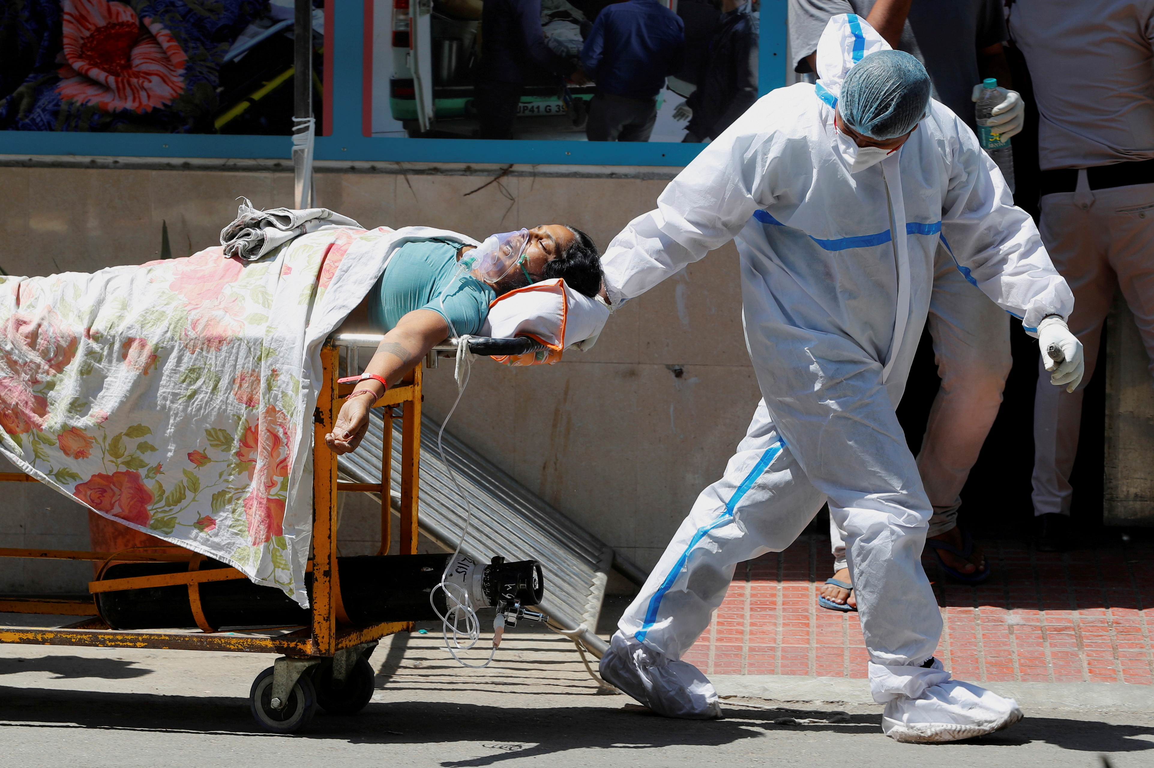 A health worker wearing personal protective equipment (PPE) carries a patient suffering from the coronavirus disease (COVID-19) outside the casualty ward at Guru Teg Bahadur hospital, in New Delhi [Adnan Abidi/Reuters]