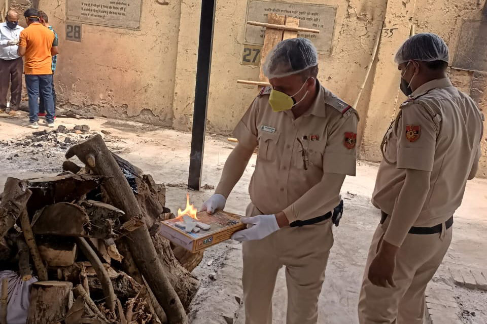 Police officer Rakesh Kumar, left, helping families perform the last rites of their loved ones at Lodhi Crematorium in New Delhi [Courtesy of Rakesh Kumar]