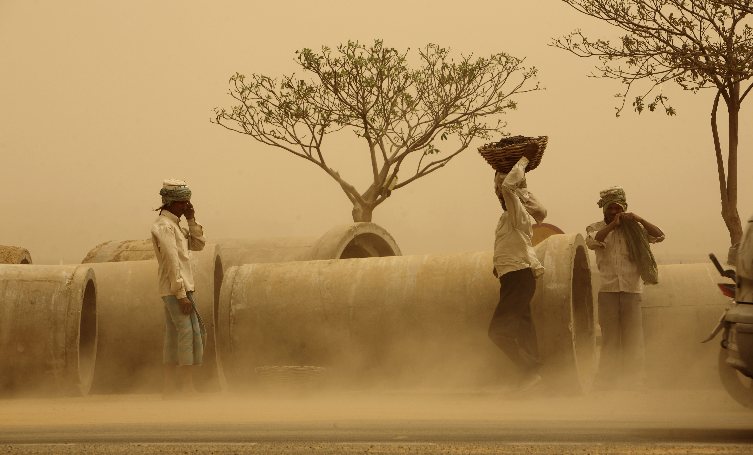 Workers carry construction material as dry hot winds blow dust at a construction site in New Delhi, India, in June 2010 [File: AP Photo/Gurinder Osan]